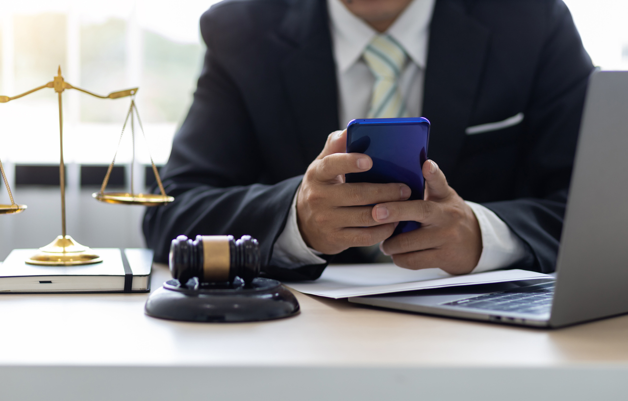 The lawyer in the office uses a cell phone. Modern text legal counseling concept.