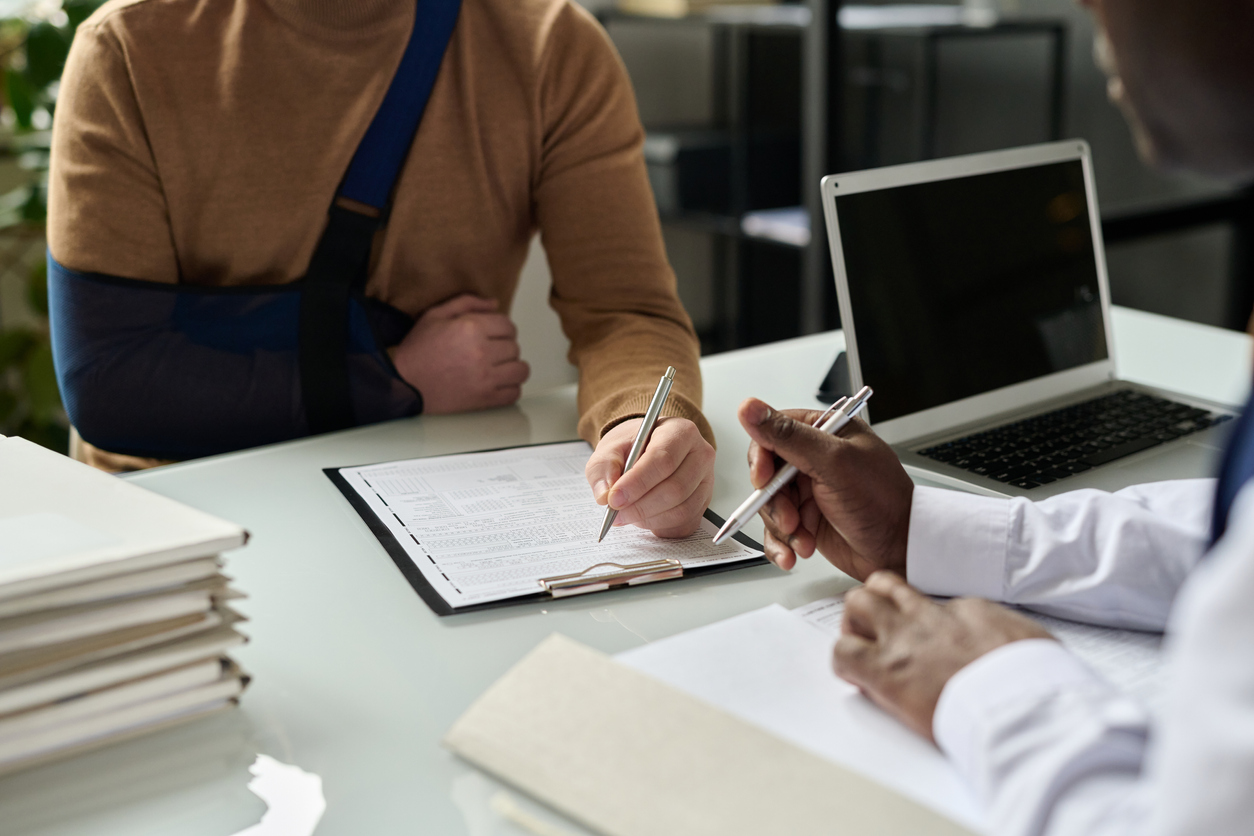 insurance form, injured hand in sling in background, copy space