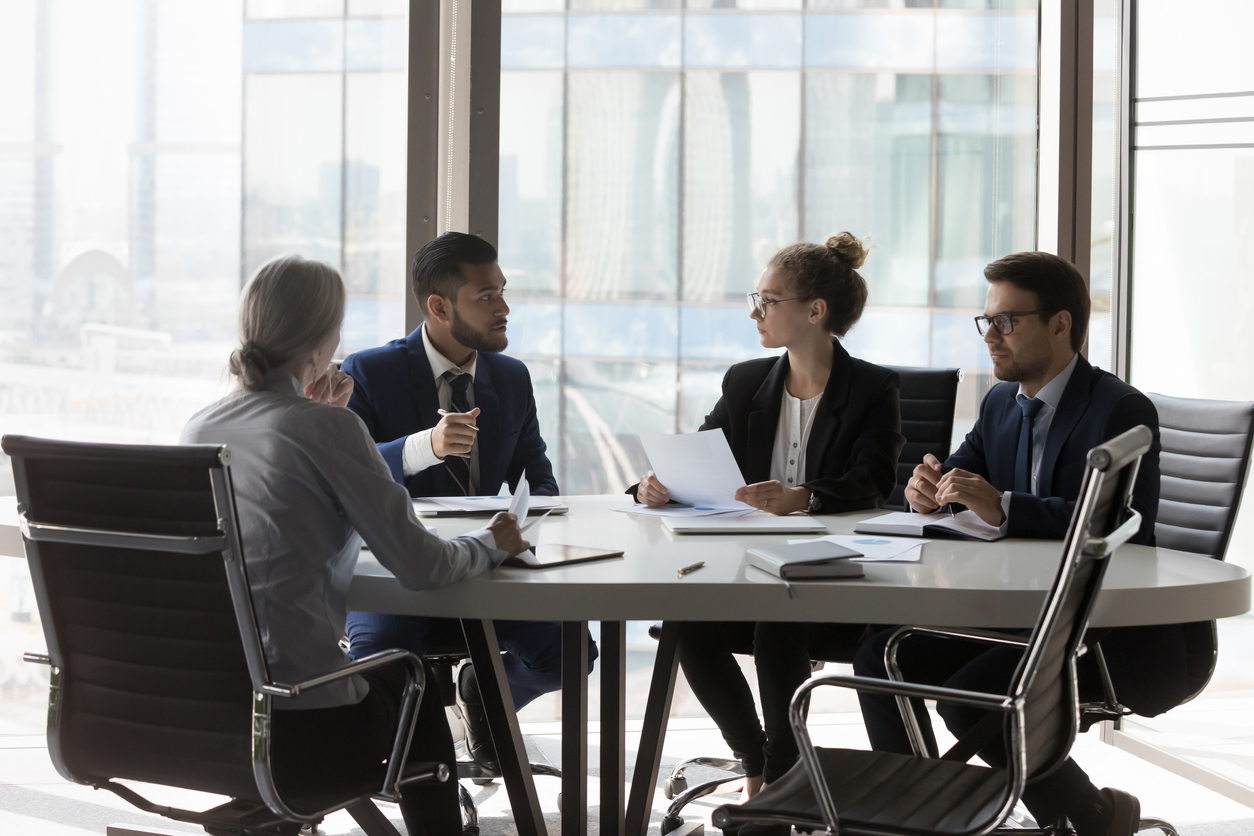 Busy millennial professional group reviewing startup marketing reports, collaborating on project. Business partners negotiating on deal, discussing agreement terms on meeting in office