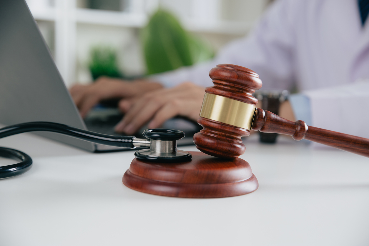 Gavel With Medical Stethoscope while doctor using laptop, Concept of medical law and medical crimes.