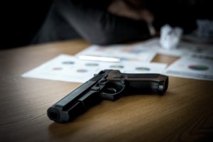 gun and us dollar bill on office desk