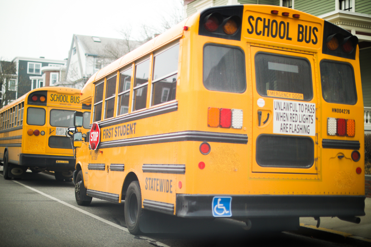 yellow school bus parked on a quiet suburban street. the bus is bright yellow with tinted windows and a stop sign on the side. photo conveys a sense of safety and nostalgia.