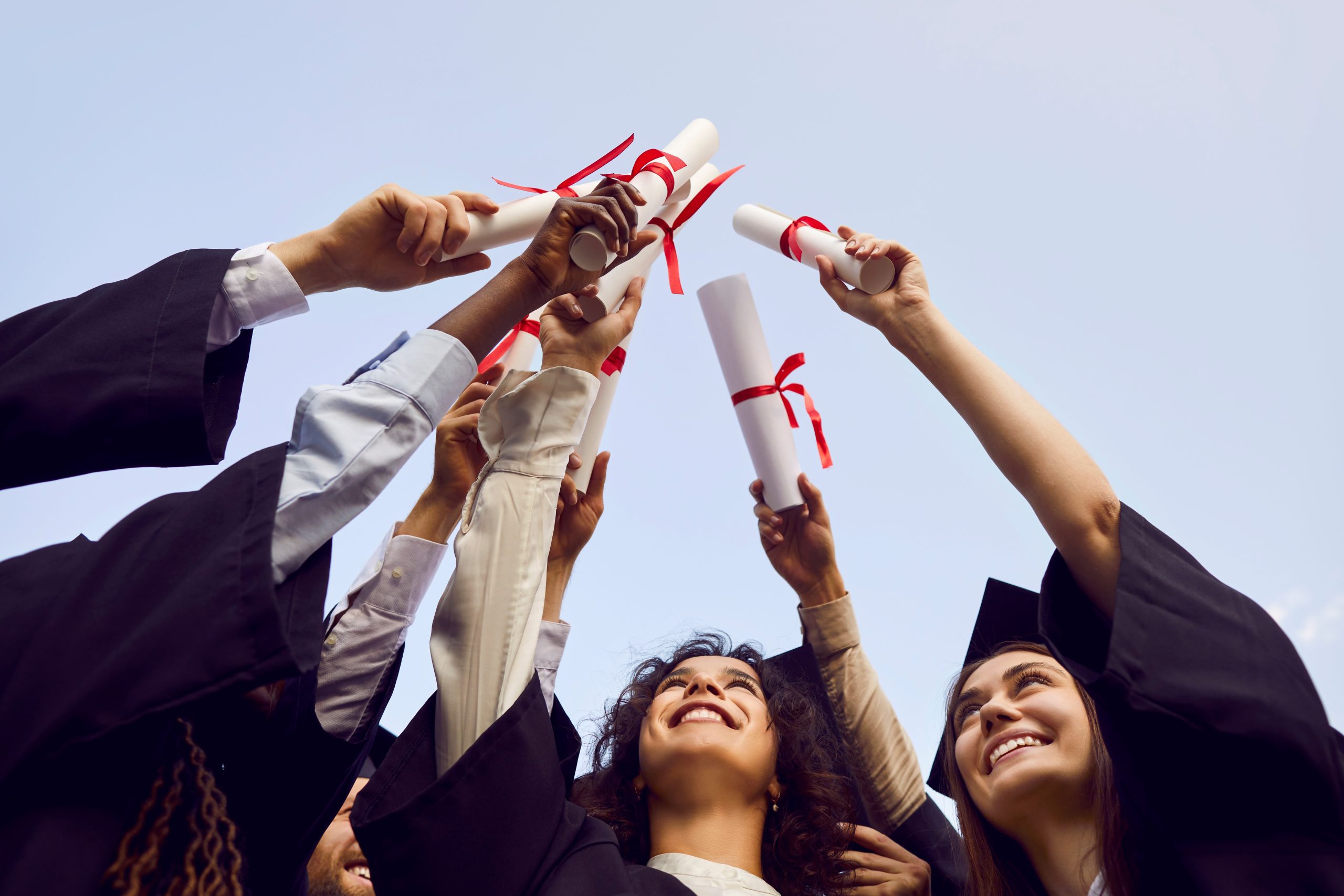 happy,graduate,students,standing,in,a,circle,in,black,robes