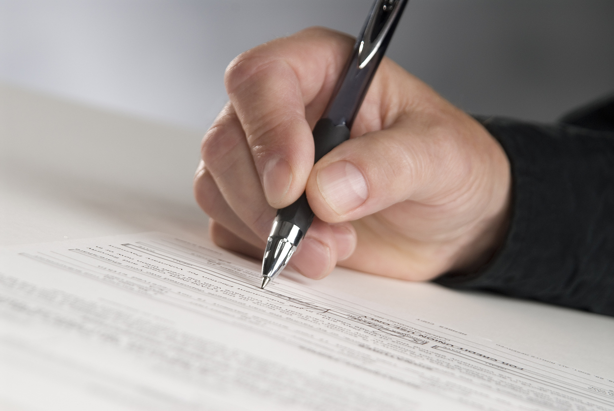 man holding pen signing document