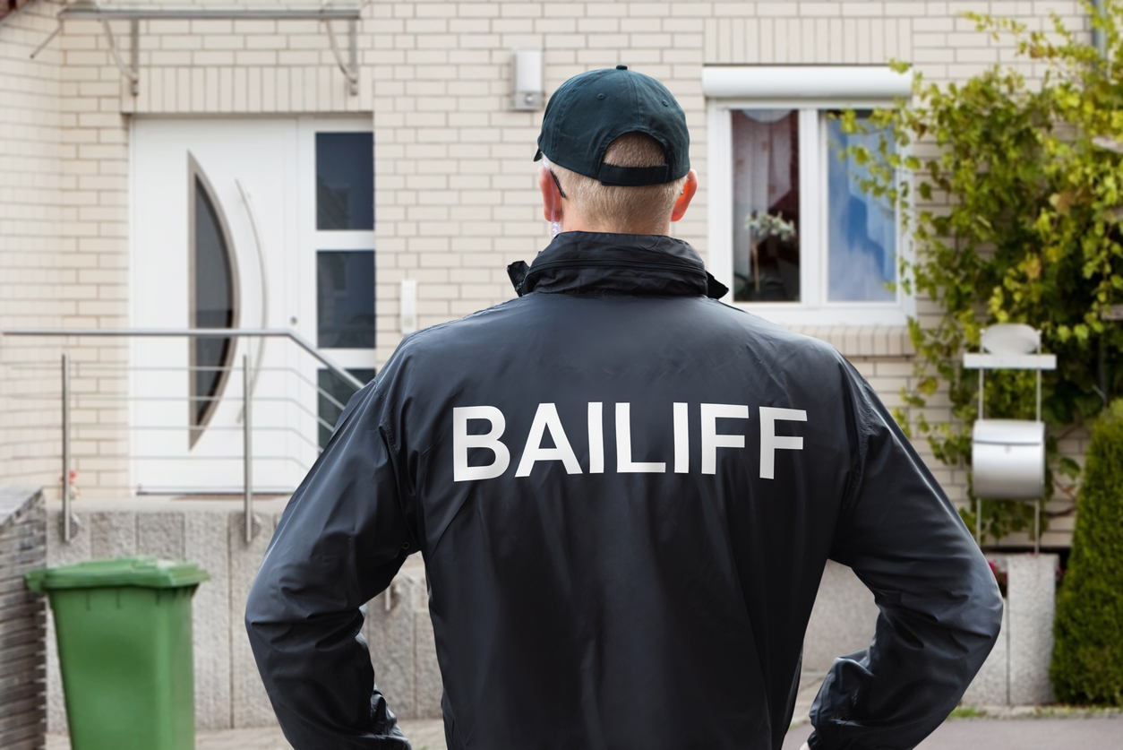 male bailiff standing at house entrance