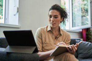 female psychologist making notes with pleasure smile while holding video call