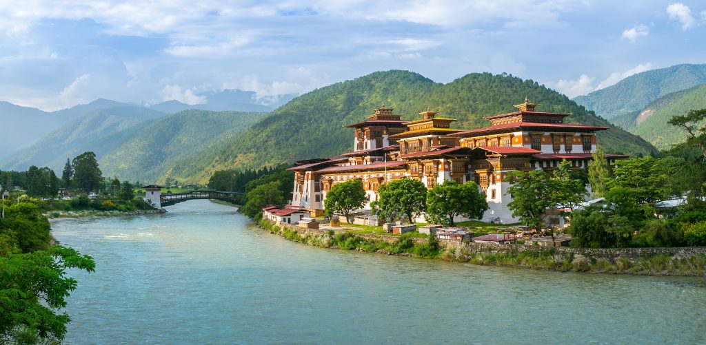 A landscape image of a monastery on a body of water surrounded by hills