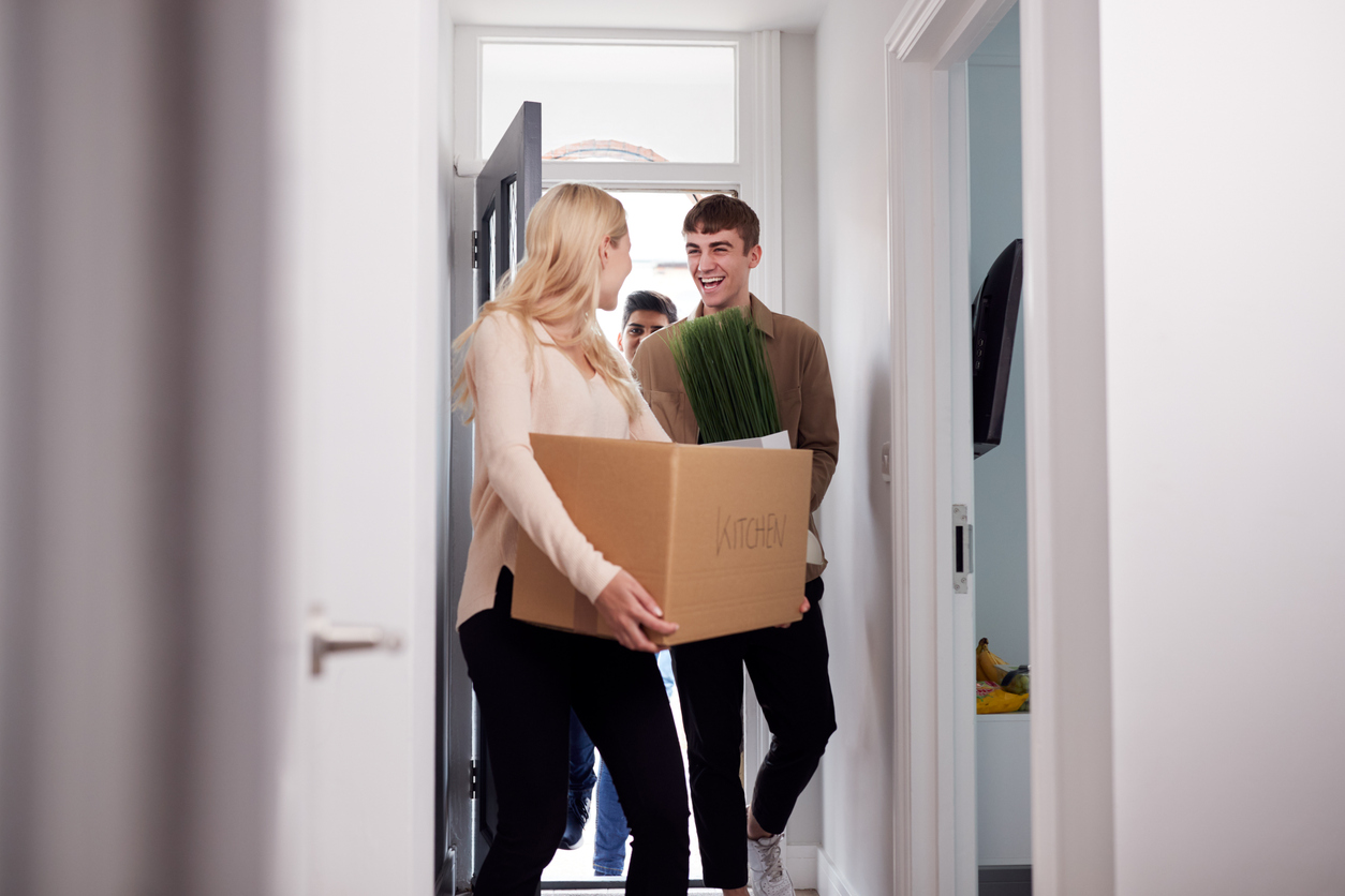 group of college student carrying boxes moving into accommodation together