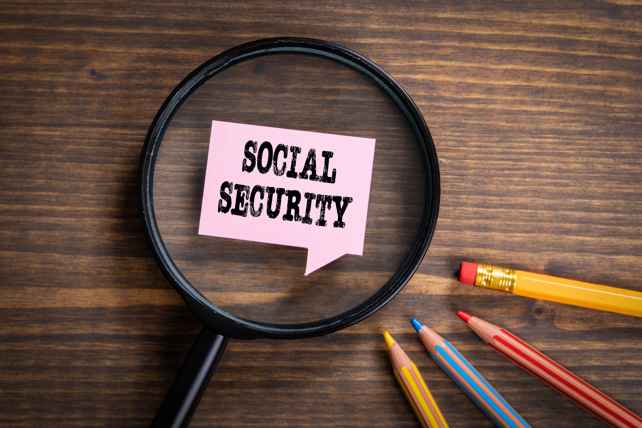 social security. black magnifying glass, speech bubble and colored pencils