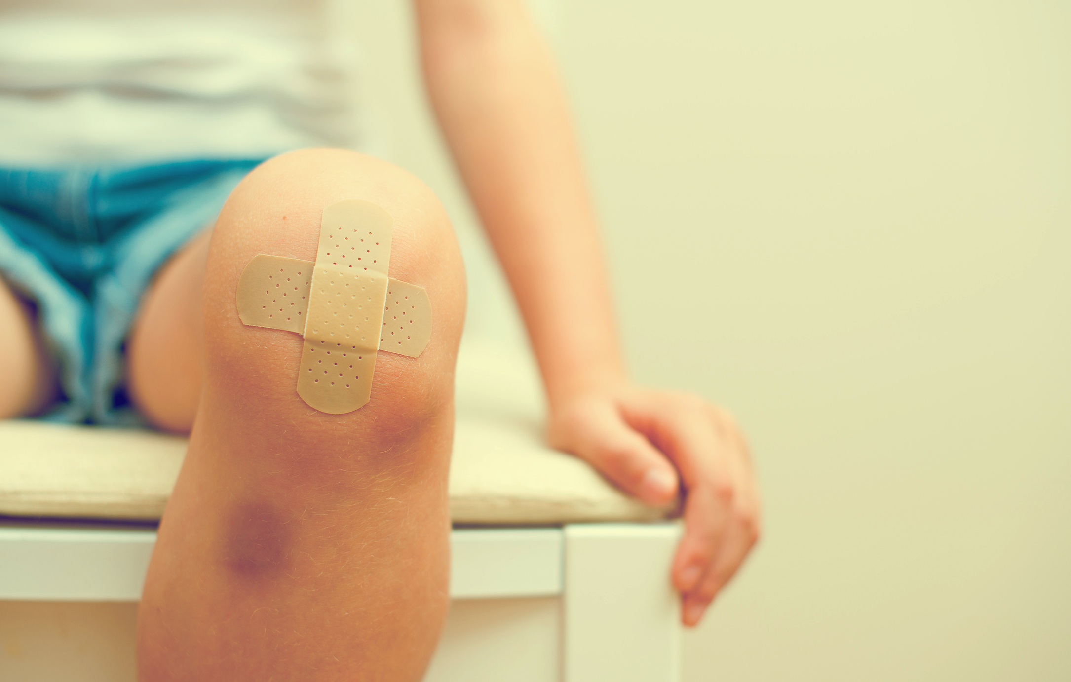 child knee with an adhesive bandage and bruise.