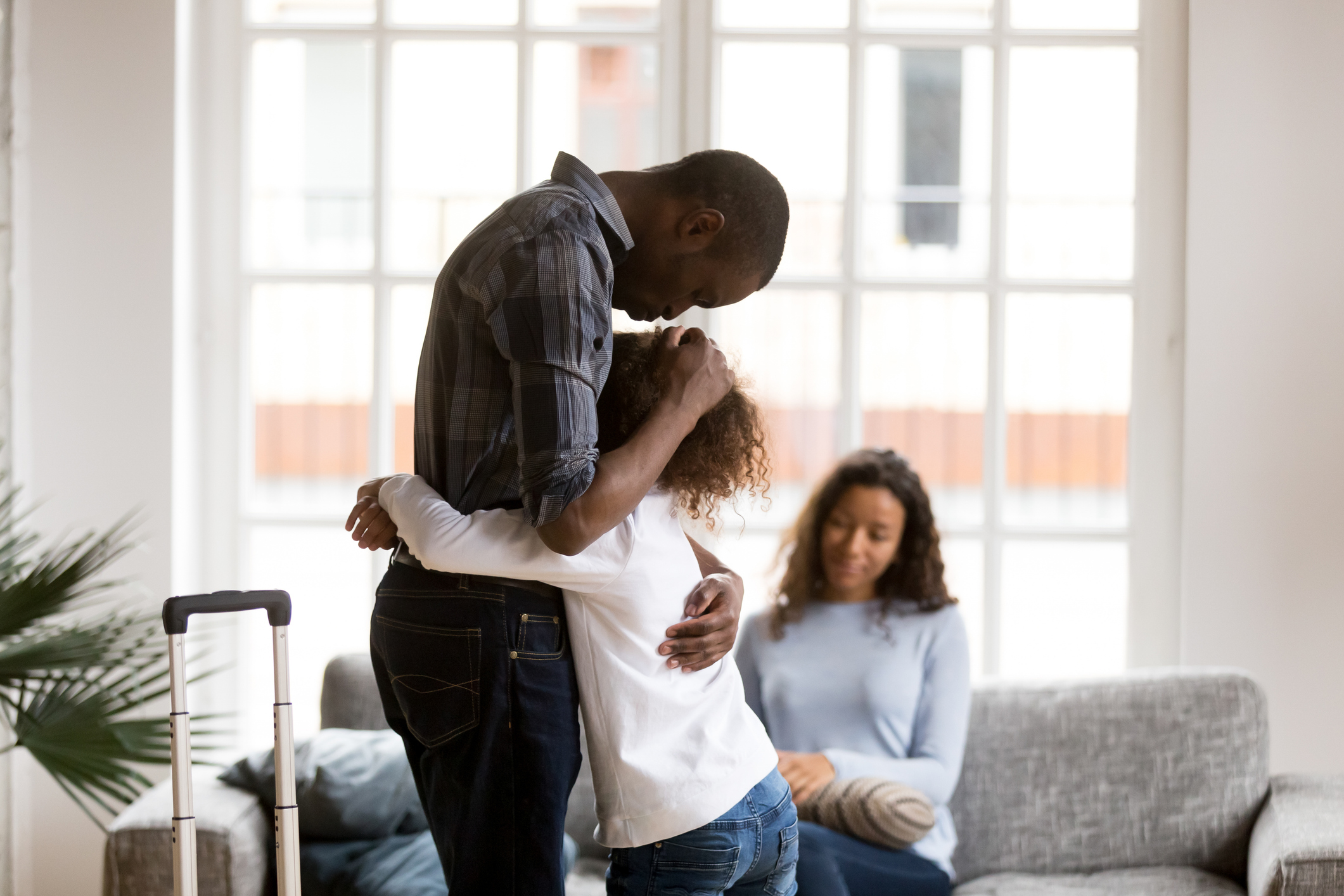 sad african american girl hug dad leaving home with suitcase