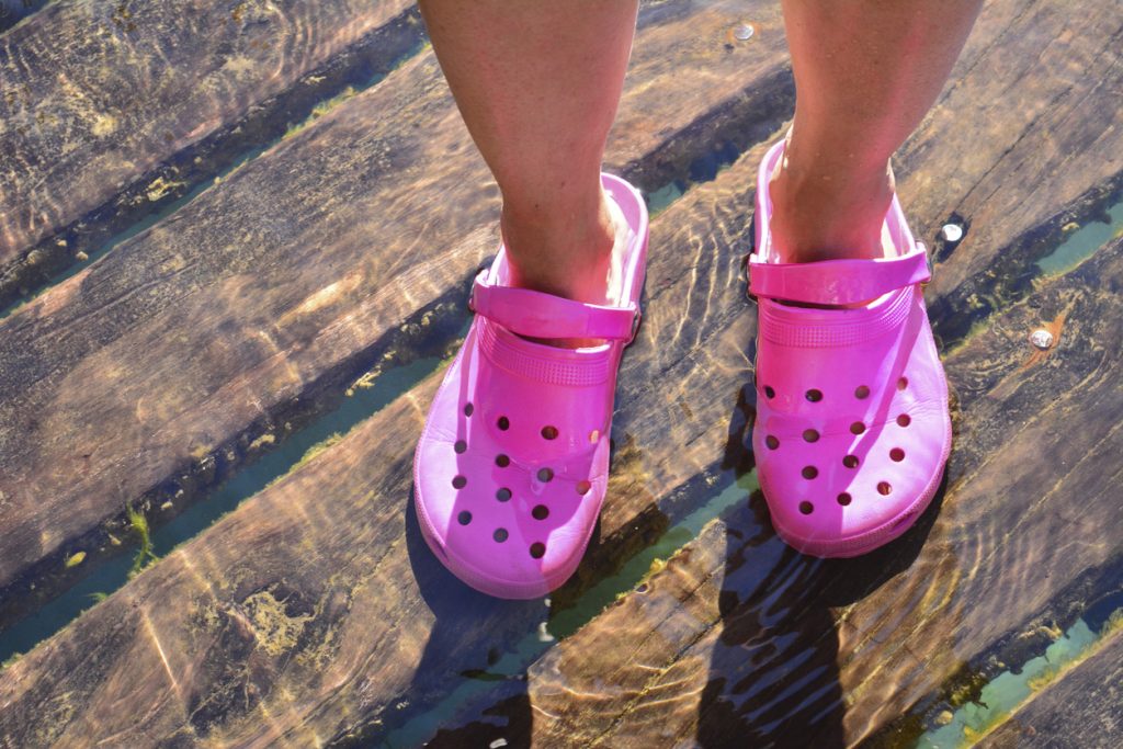 pink crocs in crystal clear water on wood