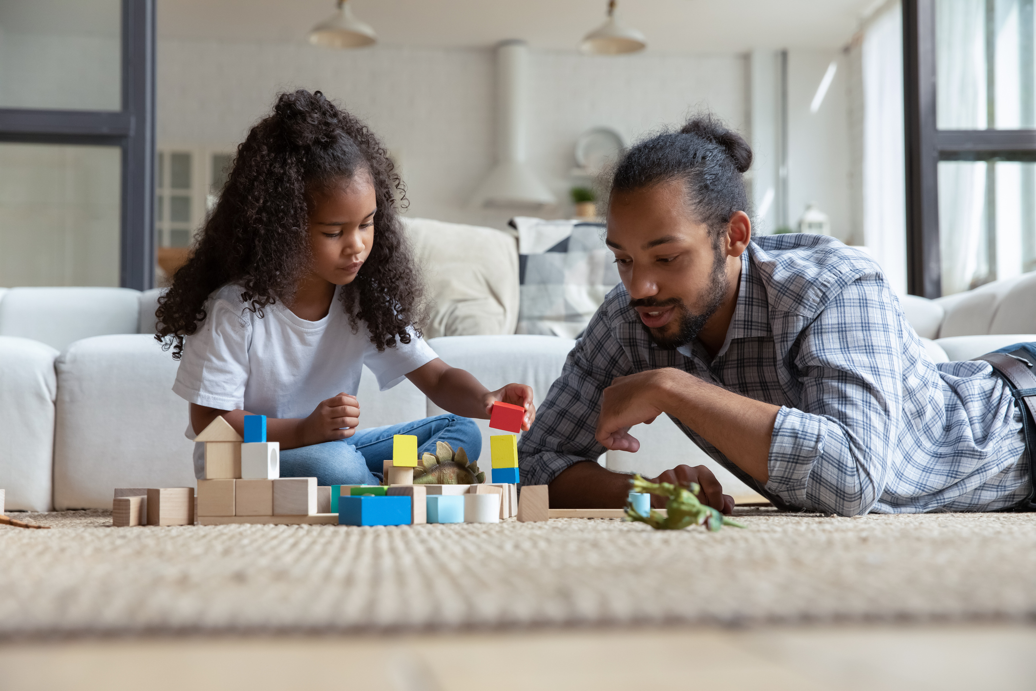 happy small kid girl playing toys with african father.