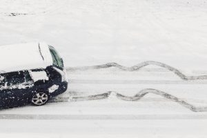 a car skids dangerously down a slippery ice and snow covered street in winter.