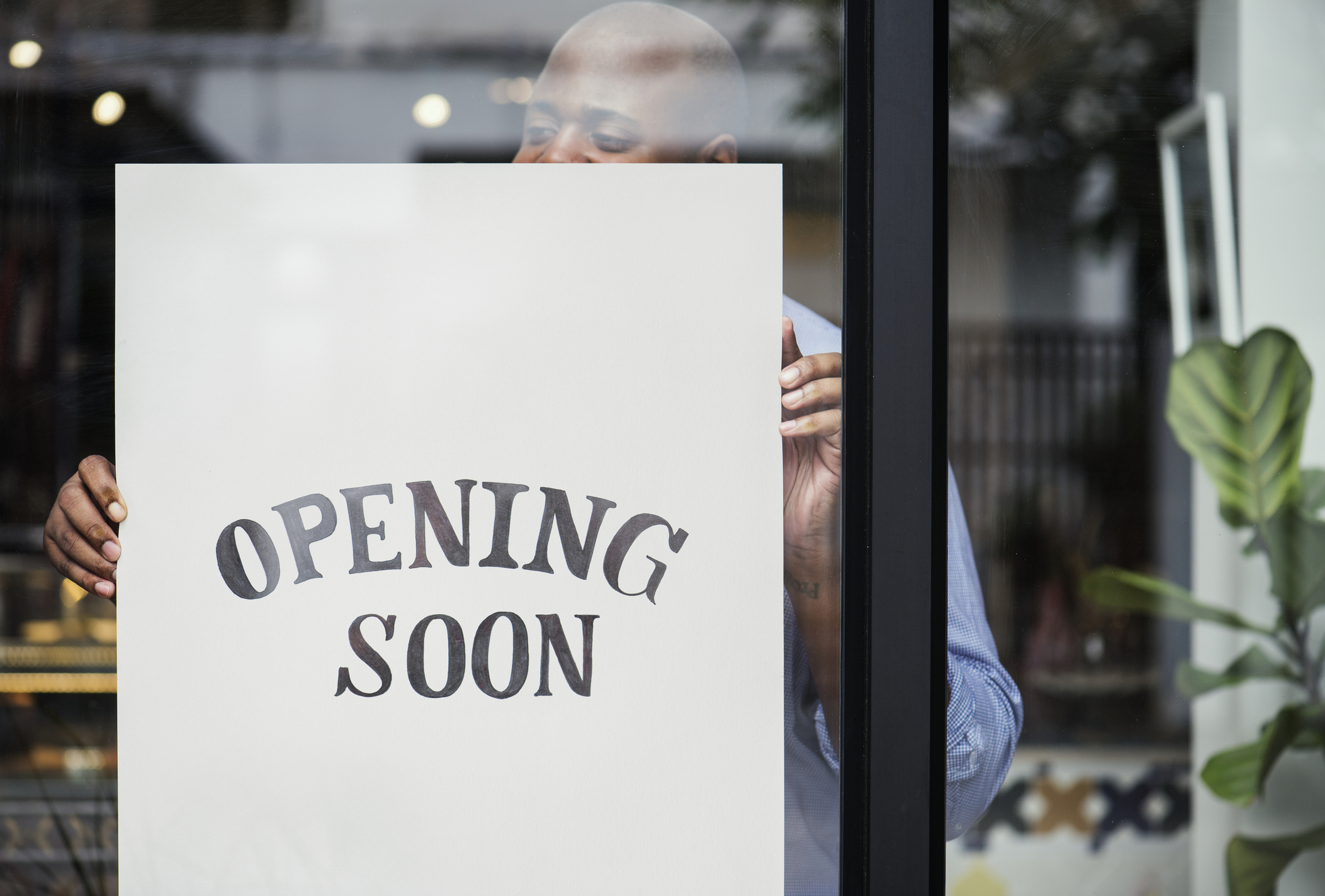 man putting on store opening soon sign