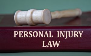 personal injury law words on a burgundy folder on the background of a judge's gavel